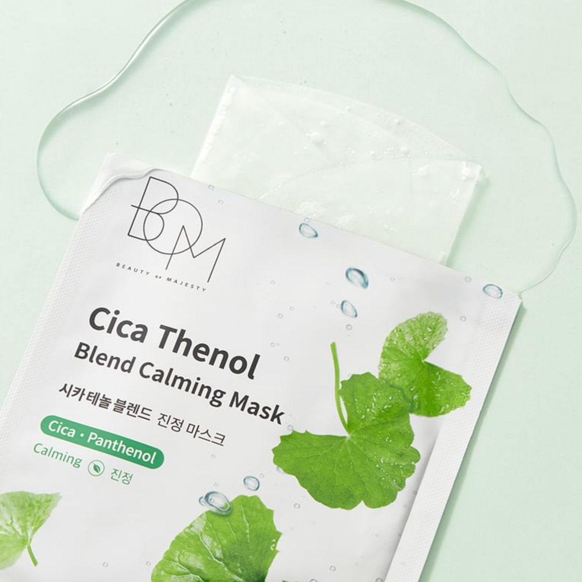 Beauty of Nature Cica Thenol Blend Calming Mask in a white packet with green leaf illustrations, placed on a pale mint green surface with a translucent gel droplet above it.