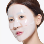 A close-up of a woman wearing a glossy, transparent peel-off face mask with eye and nose cutouts, set against a clean white background.