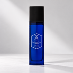 A Salveo Mathematics Toner Prestige skincare bottle in a deep cobalt blue glass with a matte black cap, standing on a light gray surface against a gray background with soft diagonal shadows.