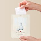 Hand pulling a sheet mask out of its packaging with a beige background