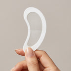 Hand holding a white silicone gel pad on a beige background