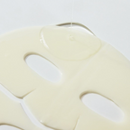 A close-up of a sheet mask with eye and mouth cutouts, shown inside a browser or app interface. The mask is a warm cream color, and the background is a light gray.